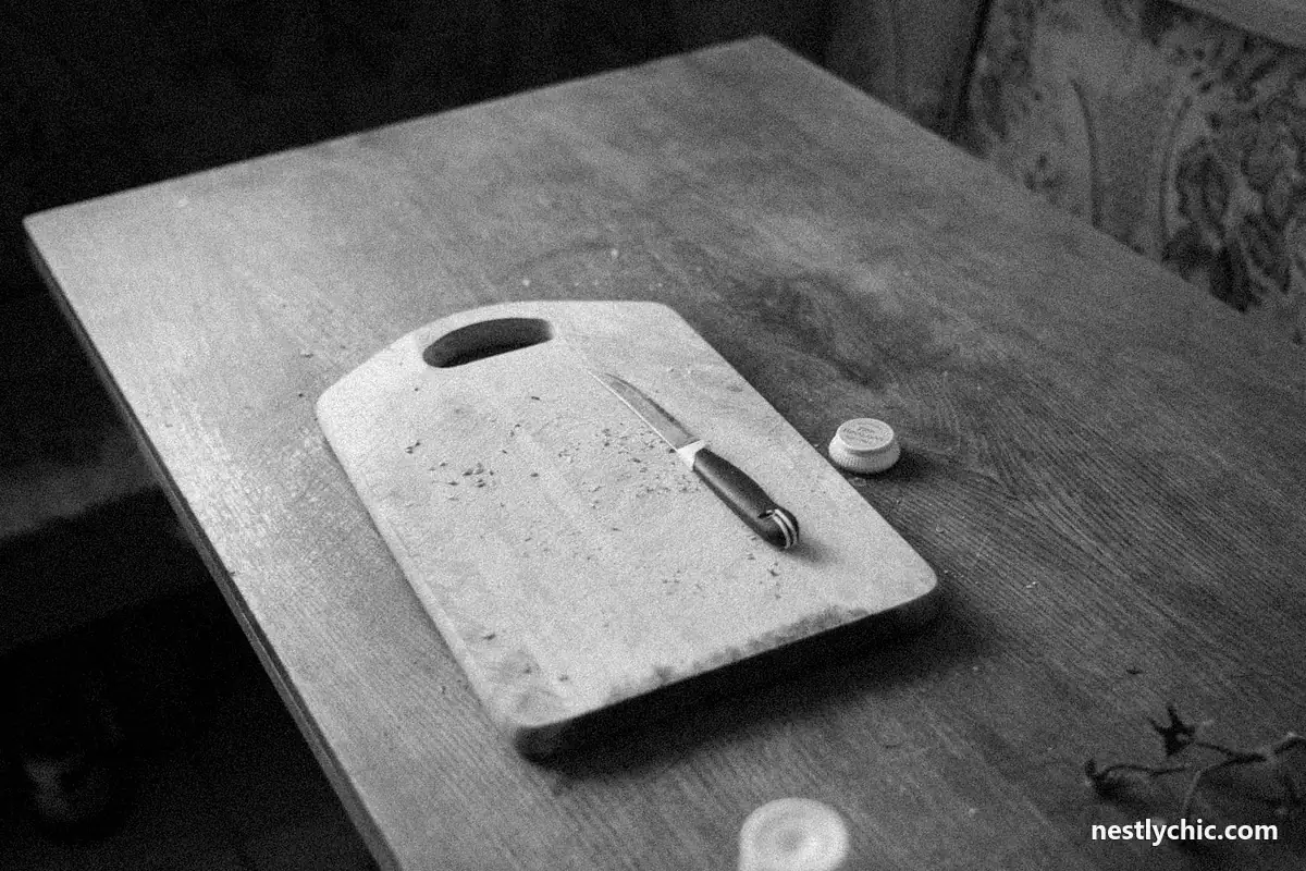 A well-used wooden chopping board and knife in a rustic kitchen