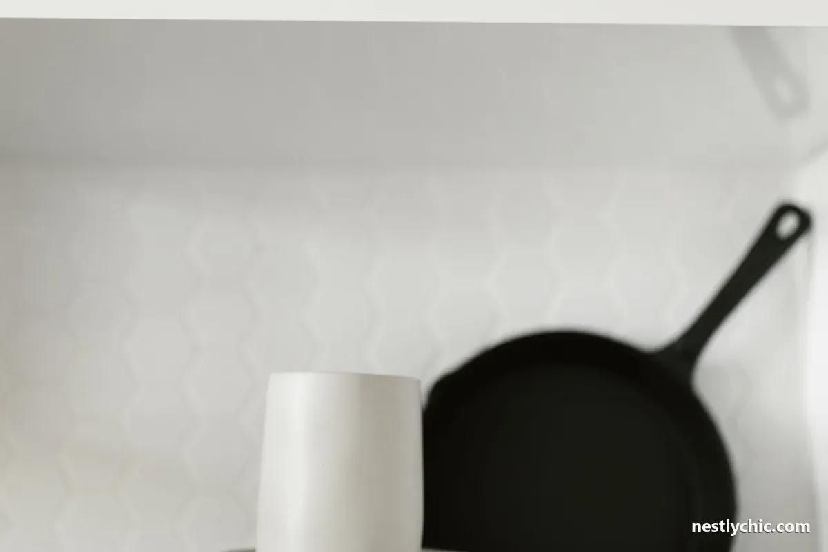 A white mug and pan on a minimalist kitchen shelf