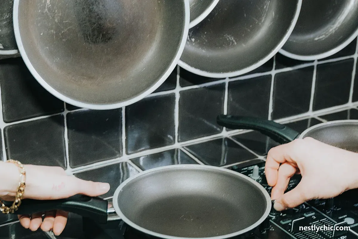 Hands lifting a frying pan from an electric stove