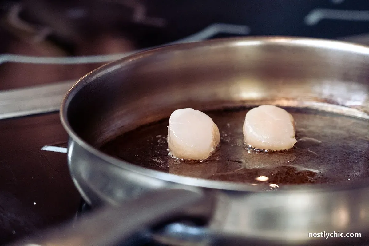 Scallops searing in a metal pan