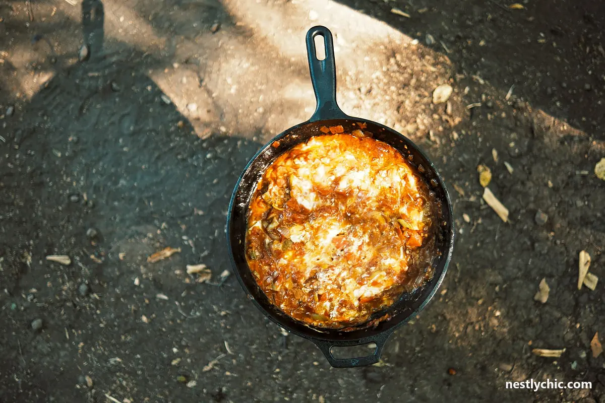 A stew cooking in a cast iron skillet over an open fire